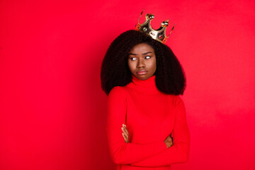 Photo of young african woman wear golden crown unhappy offended folded hands isolated over red...