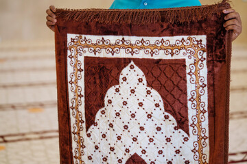 Muslim man holding his praying mat during pray time in the mosque