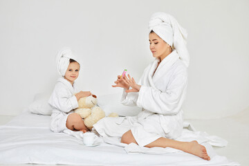 mother making manicure and daughter playing with teddy bear