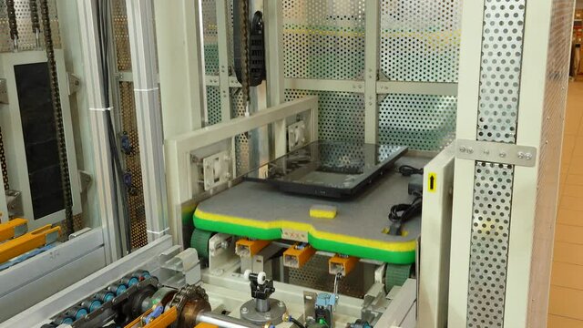 The computer case moves along a conveyor belt and is loaded into an elevator.