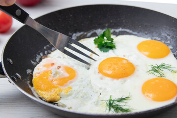Scrambled eggs in frying pan bell pepper, cherry tomato on the background of a light wooden table. National Ukrainian or belorussian food. Breakfast, lunch. Top view, selective focus, rustic style.