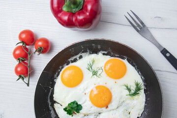 Scrambled eggs in frying pan bell pepper, cherry tomato on the background of a light wooden table. National Ukrainian or belorussian food. Breakfast, lunch. Top view, selective focus, rustic style.