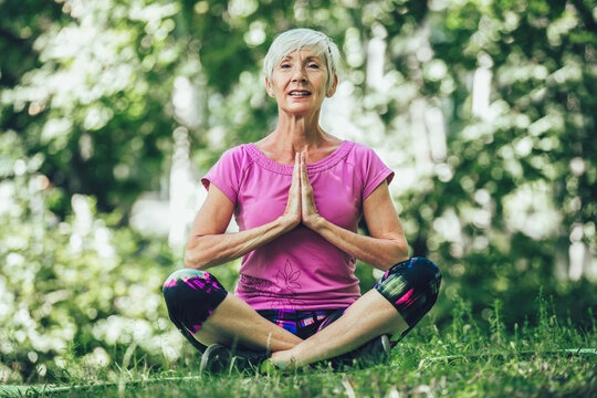 Happy mature woman practicing yoga in park. Active lifestyle