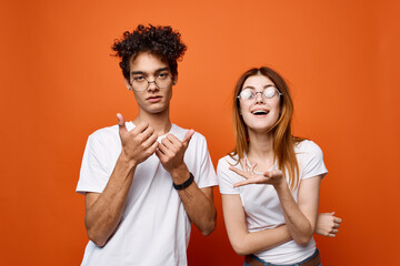 young couple in white t-shirts fun emotions orange background