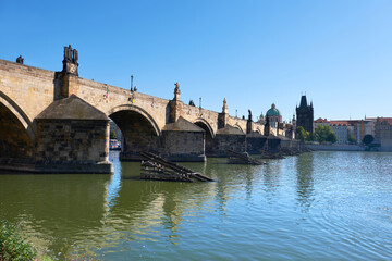 Obraz premium Charles Bridge in Prague with reflection in water. Romantic travel views of Prague, Czech Republic, in Summer with Charles Bridge, blue sky and calm water.