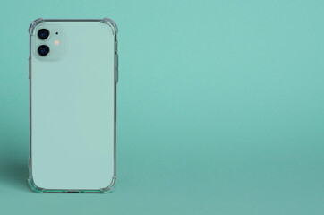 Green smartphone in clear silicone case back view. iphone 11 case mockup isolated on green...
