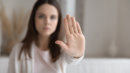 Obraz na płótnie Canvas Serious young millennial woman making hand stop gesture at home. Concerned girl showing prohibit, denial signal, palm sign saying no to domestic violence, discrimination, abuse concept. Close up