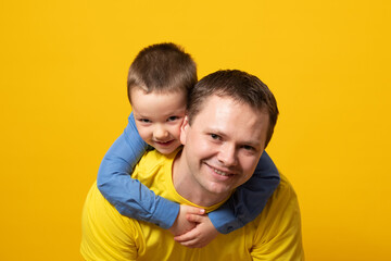 Portrait of emotional dad and his son on yellow background