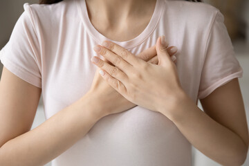 Grateful young woman applying hands on chest, expressing love, honesty. Cropped shot of girl in casual t-shirt making gratitude arms heart, thanking, sympathy, acknowledgement gesture. Close up