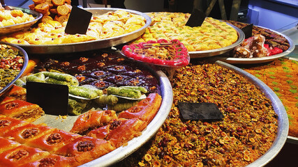 Assorted different types of baklava on large trays in the market. Oriental sweets are sold in the bazaar. Traditional delicacy of the peoples of the East, mix. Grocery background