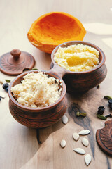 Delicious porridge with baked pumpkin seeds and spices in a ceramic bowl on a wooden table. healthy homemade breakfast. selective focus. Millet, wheat and rice porridge with pumpkin 
