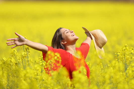 Happy woman celebrating vacation in a yellow field