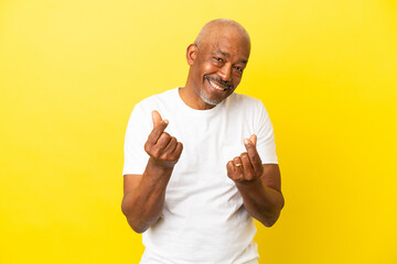 Cuban Senior isolated on yellow background making money gesture