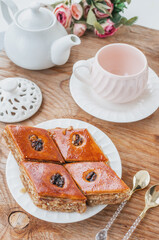 Close-up of baklava. Turkish Ramadan Arabic sweet dessert on a decorative plate, with a coffee cup in the background. Middle Eastern food baklava with nuts and honey syrup.