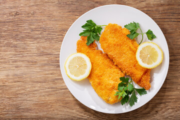 plate of chicken schnitzel on a wooden background