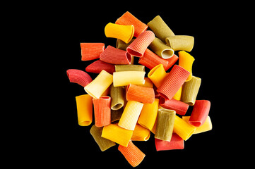 Assorted multicolored ones in rigatoni. Grocery food background, isolated on a black background. Top view