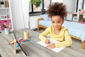 childhood, creativity and art concept - little african american girl with coloring pencils drawing...