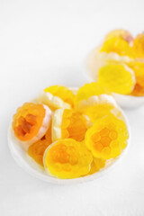 Macro photography of jelly-like craft marmalade with orange juice. The sweetness of yellow and orange jelly candies on a light table. Low depth of field, selective focus