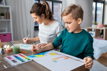 family, leisure and people concept - mother and little son with colors and paper drawing at home