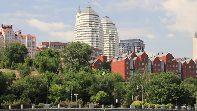 ars go along the street against the background of buildings, towers, skyscrapers, park in the city  Dnepropetrovsk, Dnipro, Ukraine. Beautiful view from Monastyrsky Island in spring and summer
