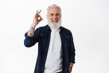 Alright. Handsome senior man laughing, showing okay OK sign and nod in approval, praise good work,...