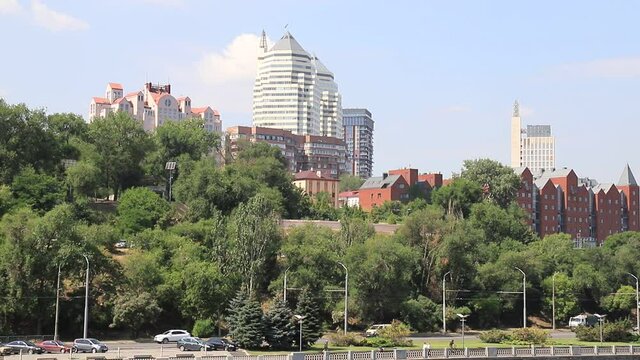 ars go along the street against the background of buildings, towers, skyscrapers, park in the city  Dnepropetrovsk, Dnipro, Ukraine. Beautiful view from Monastyrsky Island in spring and summer