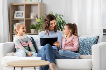 people, family and technology concept - happy mother and two daughters with tablet pc computer at home