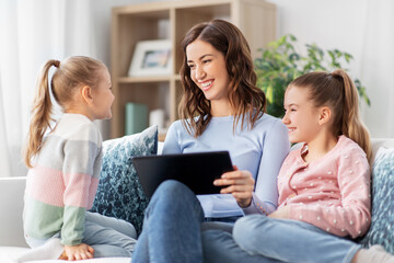 people, family and technology concept - happy mother and two daughters with tablet pc computer at home