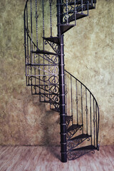 Vintage metal spiral staircase on the background of the old wall and wooden floor © Андрей Журавлев