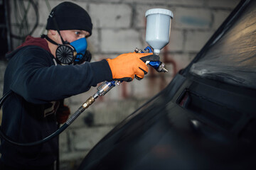 man paints a car, treatment of the body with epoxy primer.
