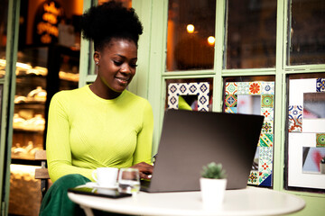 Businesswoman drinking coffee in cafe. Beautiful woman working on laptop in coffee shop.