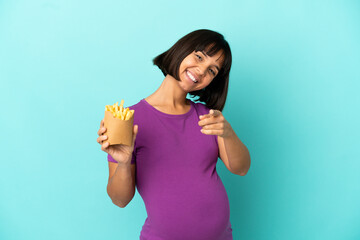 Pregnant woman holding fried chips over isolated background pointing front with happy expression