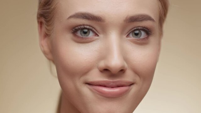 Natural beauty. Attractive young blonde lady smiling to camera over beige studio background, slow motion