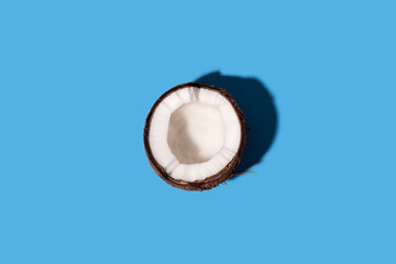 Fresh coconut cut in half sliced on a pastel blue background.
