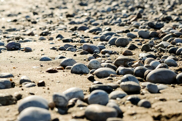 Fototapeta na wymiar A close up view of smooth polished multicolored stones washed ashore on the beach. High quality photo