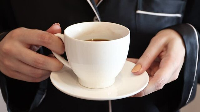 Young woman with a cup of coffee in her hands. Gitl holding a cup