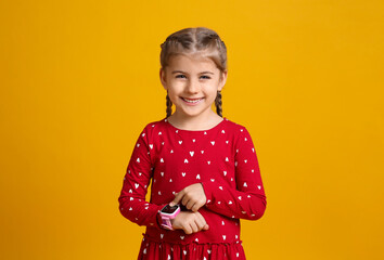 Little girl with smart watch on yellow background