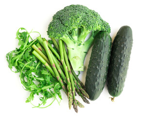 still life from green farm vegetables, arugula, broccoli, asparagus and cucumbers on white background