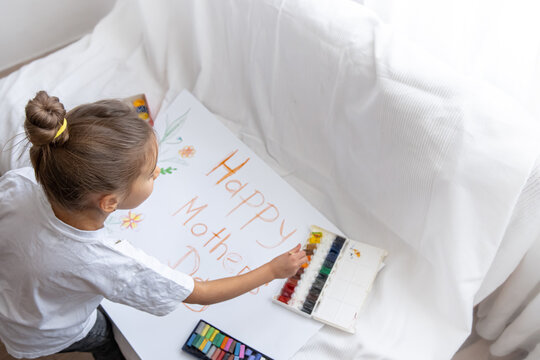 Little girl drawing mothers day holiday card top view.