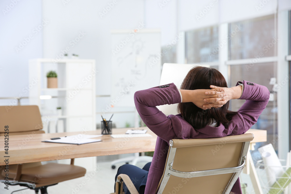 Wall mural woman relaxing in office chair at workplace, back view