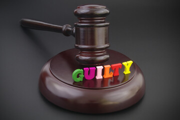 Judge gavel and word guilty on black table, crime and law