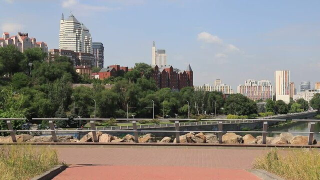 ars go along the street against the background of buildings, towers, skyscrapers, park in the city  Dnepropetrovsk, Dnipro, Ukraine. Beautiful view from Monastyrsky Island in spring and summer