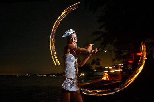 Young woman with fire fans performing fire show at beach