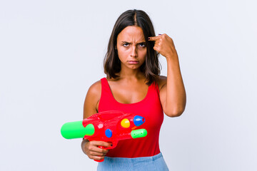 Fototapeta na wymiar Young mixed race woman holding a water gun isolated focused on a task, keeping forefingers pointing head.