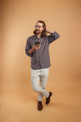 White ginger man wearing eyeglasses smiling and using cellphone