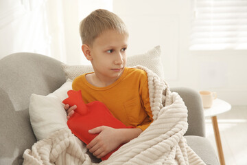 Ill boy with hot water bottle suffering from cold at home