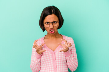 Young mixed race woman isolated on blue background upset screaming with tense hands.