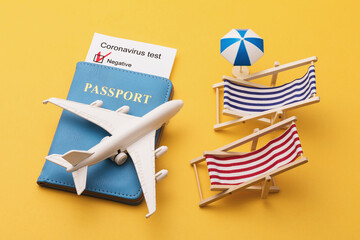 Passport, coronavirus test results, toy plane and sun loungers on yellow background, modern air travel concept