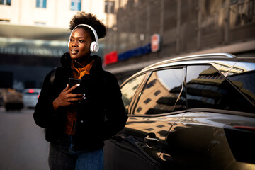 Young african woman outdoors. Beautiful woman listening to music while walking through the city..