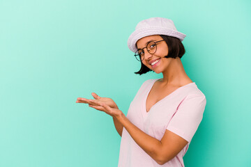 Young mixed race woman isolated on blue background holding a copy space on a palm. © Asier